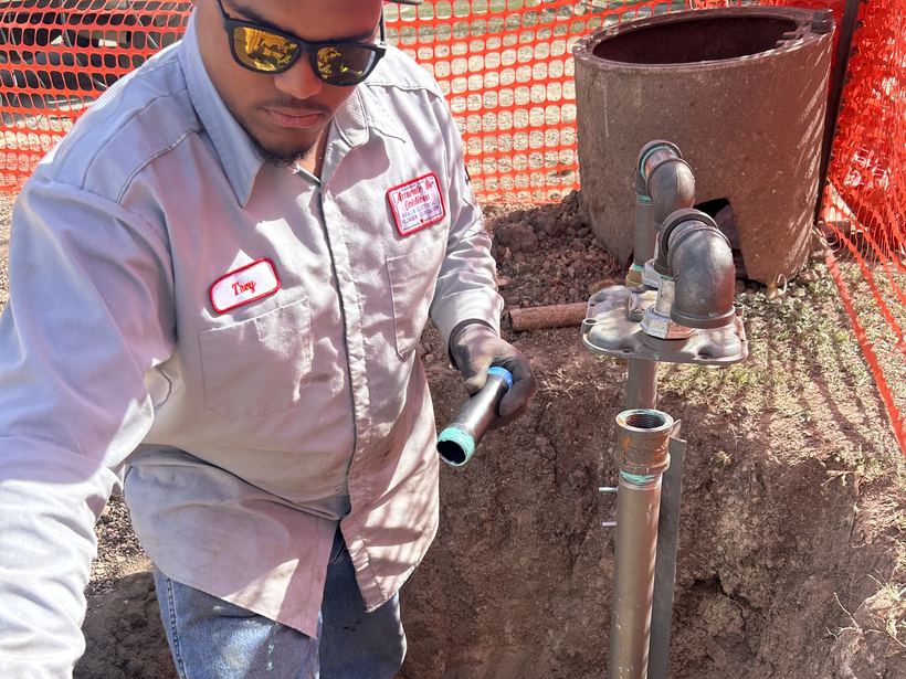 Technician assembling a water riser in a pit